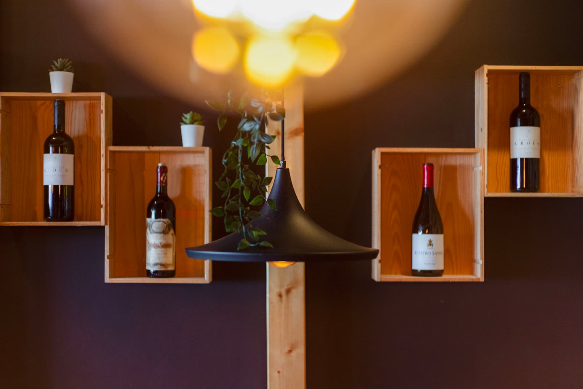 Parede com nichos de madeira e garrafas de vinho no Coral Food & Wine