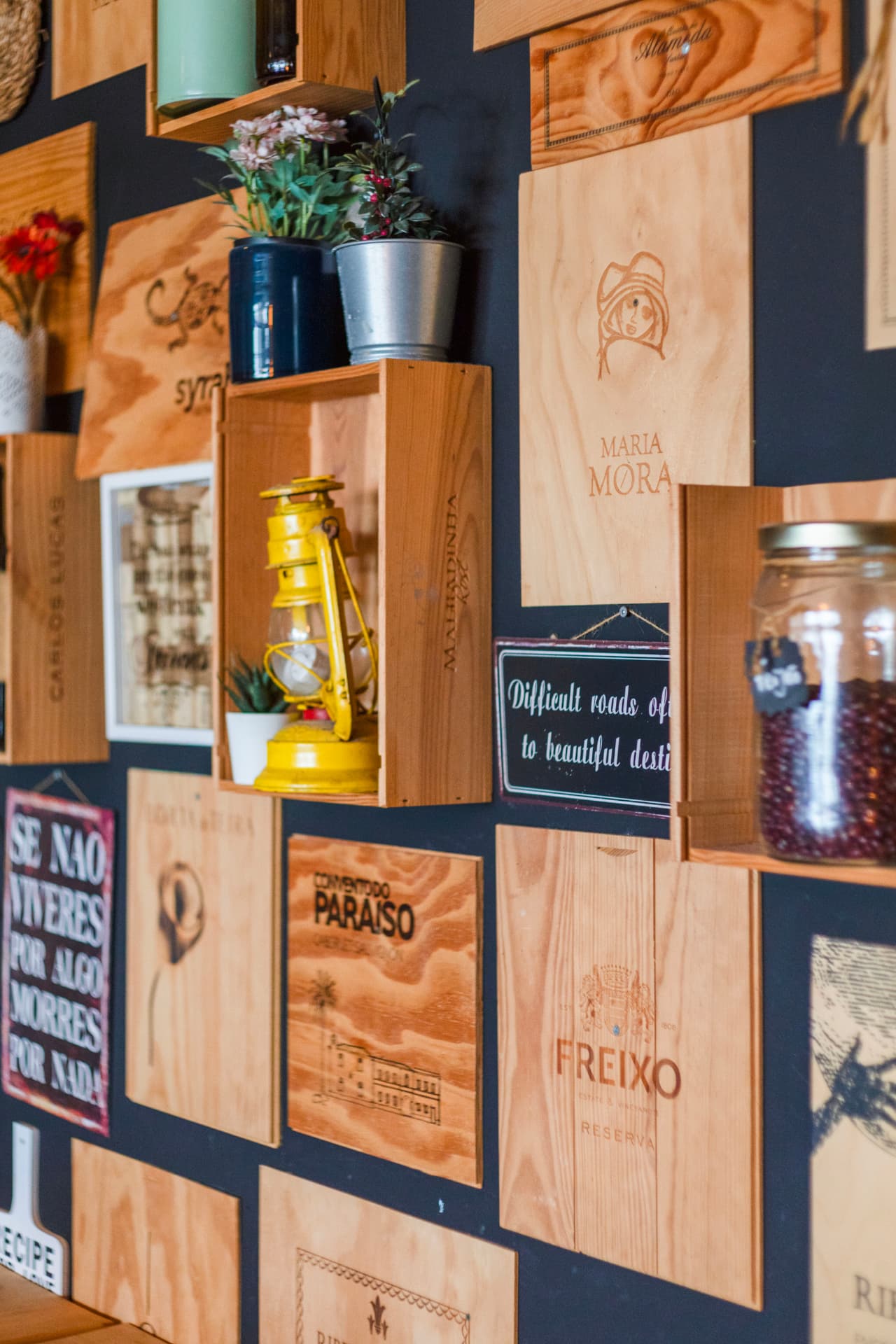 Parede decorada com tampas de caixas de vinho no Coral Food & Wine